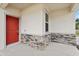 A welcoming front porch featuring a red door, stone accents, and a view of the front yard at 3495 Salvia Ct, Tavares, FL 32778