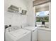 Laundry room with a front load washer and dryer, folding shelf, and a window overlooking the street at 3495 Salvia Ct, Tavares, FL 32778