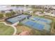 Aerial view of multiple blue and green tennis courts with shelters by a pond within the community at 569 Vista Sol Dr, Davenport, FL 33837