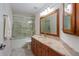 Bathroom featuring wood cabinets, granite counters, and a glass-enclosed shower at 10384 Se 41St Ter, Belleview, FL 34420