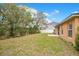 View of the backyard featuring a grassy area, lush trees, and a white fence at 114 Alexandria Cir, Deland, FL 32724