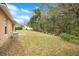 Image of the home's backyard featuring a grassy area, lush trees, and exterior seating at 114 Alexandria Cir, Deland, FL 32724