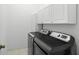 Modern laundry room with side by side washer and dryer and white cabinets above at 1243 Osprey Way, Apopka, FL 32712