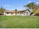 Expansive backyard showcasing a well-maintained lawn and the home's exterior with its tile roof and covered patio at 1690 Oneco Ave, Winter Park, FL 32789