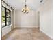 Neutral dining room with travertine floors, a decorative chandelier, and a large window for natural light at 1690 Oneco Ave, Winter Park, FL 32789