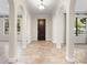 Elegant foyer featuring arched entryways, a dark wood front door, neutral paint and travertine tile flooring at 1690 Oneco Ave, Winter Park, FL 32789