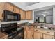 Functional kitchen features black appliances, wood cabinets and view to living area at 1821 Christina Lee Ln, St Cloud, FL 34769