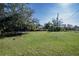 Large, grassy backyard featuring mature trees with a trampoline and a fenced area in the background at 2413 Spingarn Ct, Orlando, FL 32811