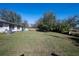 Spacious backyard showing a home's exterior, lush green grass, and mature trees under a clear sky at 2413 Spingarn Ct, Orlando, FL 32811