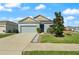 Single-story home featuring a two car garage, neutral toned exterior, and manicured front lawn at 301 E Fiesta Key Loop, Deland, FL 32720