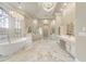 Luxurious bathroom with marble flooring, dual vanities, soaking tub, and elegant lighting fixtures at 3037 Seigneury Dr, Windermere, FL 34786