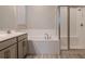 Bathroom featuring double vanity, soaking tub, and separate tiled shower with glass doors at 367 Sofia Ln, Lake Alfred, FL 33850