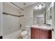 Cozy bathroom featuring a shower-tub combo, vanity with cherry-wood cabinets, and polka dot wallpaper at 4019 Alcott Cir, Orlando, FL 32828