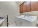 Bright laundry room features a white washer and dryer with convenient overhead cabinet storage at 4019 Alcott Cir, Orlando, FL 32828