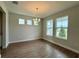 Open dining room featuring wood-look tile flooring, modern chandelier, and natural lighting from multiple windows at 780 Pointe Emerson Blvd, Apopka, FL 32703
