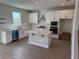 Bright, well-equipped kitchen with white cabinets, a central island, stainless appliances, and wood-look floors at 780 Pointe Emerson Blvd, Apopka, FL 32703