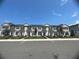 New townhomes featuring modern exteriors, charming red doors, and landscaped yards under a blue sky at 780 Pointe Emerson Blvd, Apopka, FL 32703