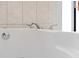 Close-up of a white bathtub with chrome faucet fixtures and marble tile backsplash at 9532 Bay Vista Estates Blvd # 1, Orlando, FL 32836