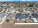 An aerial view of homes in a suburban neighborhood with well-maintained lawns and mature trees under a clear sky at 1230 Woodlark Dr, Haines City, FL 33844