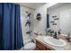 Well-lit bathroom featuring a shower with blue curtain, a sink, and a granite countertop at 1230 Woodlark Dr, Haines City, FL 33844