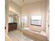 Well-lit bathroom featuring a garden tub, glass shower, tile floors, and modern vanity at 12017 Fambridge, Orlando, FL 32837
