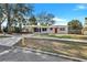 Quaint single story home with a carport, red front door, and traditional landscaping at 1202 Ferndell Rd, Orlando, FL 32808