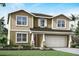 Two-story home featuring shake accents, columns, a two-car garage, and fresh landscaping at 13154 Pergola Ave, Orlando, FL 32832