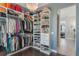 A custom walk-in closet with ample shelving and a decorative chandelier features dark wood floors and storage for clothes and shoes at 25850 Crossings Bluff Ln, Sorrento, FL 32776