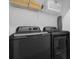 A laundry room featuring a gray, front-loading washer and dryer set with overhead storage shelves at 2945 Simile St, Kissimmee, FL 34746