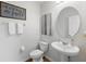 Stylish half bathroom featuring an oval mirror, pedestal sink, and charming wall art at 3270 Mt Vernon Way, Kissimmee, FL 34741