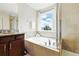Bright bathroom featuring a double vanity, soaking tub, glass-enclosed shower, and a large window at 3270 Mt Vernon Way, Kissimmee, FL 34741