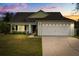 Charming single-story home with a well-maintained lawn and attached two-car garage, set against a colorful twilight sky at 3304 Kelsey Ln, St Cloud, FL 34772