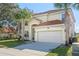 Two-story house featuring a terra cotta tile roof, a two-car garage, and palm trees in the front yard at 390 Miro Dr, Davenport, FL 33837