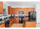 Well-lit kitchen boasts wooden cabinets, granite countertops, black appliances and a functional center island at 390 Miro Dr, Davenport, FL 33837