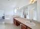 Bright bathroom with dual sinks, large mirror, and neutral tile at 603 Deauville Ct, Kissimmee, FL 34758