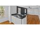 Kitchen area with white cabinetry, stainless sink, dishwasher, and hardwood flooring at 627 N Hyer Ave, Orlando, FL 32803