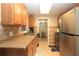 Efficient kitchen featuring updated appliances, warm wood cabinetry, and a pass-through to the living area at 7119 Leighton Way, Orlando, FL 32822