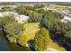 Aerial view of a golf course bordering a lake, lined with mature trees in a tranquil community setting at 721 Polo Park Blvd, Davenport, FL 33897