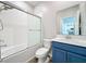 Bathroom featuring a shower over tub with glass doors, a blue vanity, and tiled walls at 917 Carmillion Ct, Groveland, FL 34736