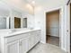 A bright bathroom featuring double sinks, white cabinets, and a walk-in closet at 917 Carmillion Ct, Groveland, FL 34736