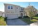 Two-story home featuring a neutral stucco finish, arched entryway, paver driveway, and attached two-car garage at 917 Carmillion Ct, Groveland, FL 34736