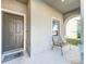Covered front porch area with a single chair and a view of the home's exterior and landscaping at 917 Carmillion Ct, Groveland, FL 34736