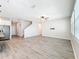 Open-concept living room with light wood-look floors, ceiling fan, and stainless steel appliances in kitchen at 917 Carmillion Ct, Groveland, FL 34736