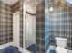 Stylish bathroom featuring a shower with glass door, blue tile floors, and patterned wallpaper, creating a unique space at 9501 Tavistock Rd, Orlando, FL 32827