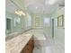 Elegant bathroom featuring marble floors, double sink vanity, soaking tub, and soft natural light at 9501 Tavistock Rd, Orlando, FL 32827