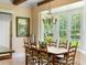 Cozy dining area showcasing a wooden table, chairs, and views of the landscaped backyard through bay windows at 9501 Tavistock Rd, Orlando, FL 32827