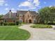 A charming two-story brick home features a beautifully landscaped front yard and a curved driveway at 9501 Tavistock Rd, Orlando, FL 32827