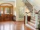 Inviting foyer with gleaming hardwood floors, staircase with decorative iron, and a wood entry door at 9501 Tavistock Rd, Orlando, FL 32827