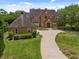 Brick house with a circular driveway, lush green lawn, and manicured landscaping at 9501 Tavistock Rd, Orlando, FL 32827