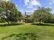 Stately home with a large front yard, mature trees, and classic architectural details at 9501 Tavistock Rd, Orlando, FL 32827